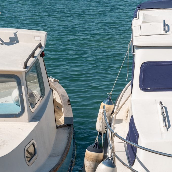 Zwei Boote liegen nebeneinander auf ruhigem, blauem Wasser und warten auf ein Wertgutachten