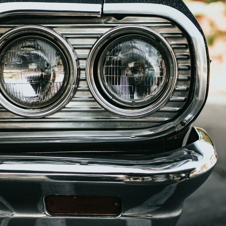 Nahaufnahme der Frontscheinwerfer eines klassischen Autos mit verchromtem Grill.